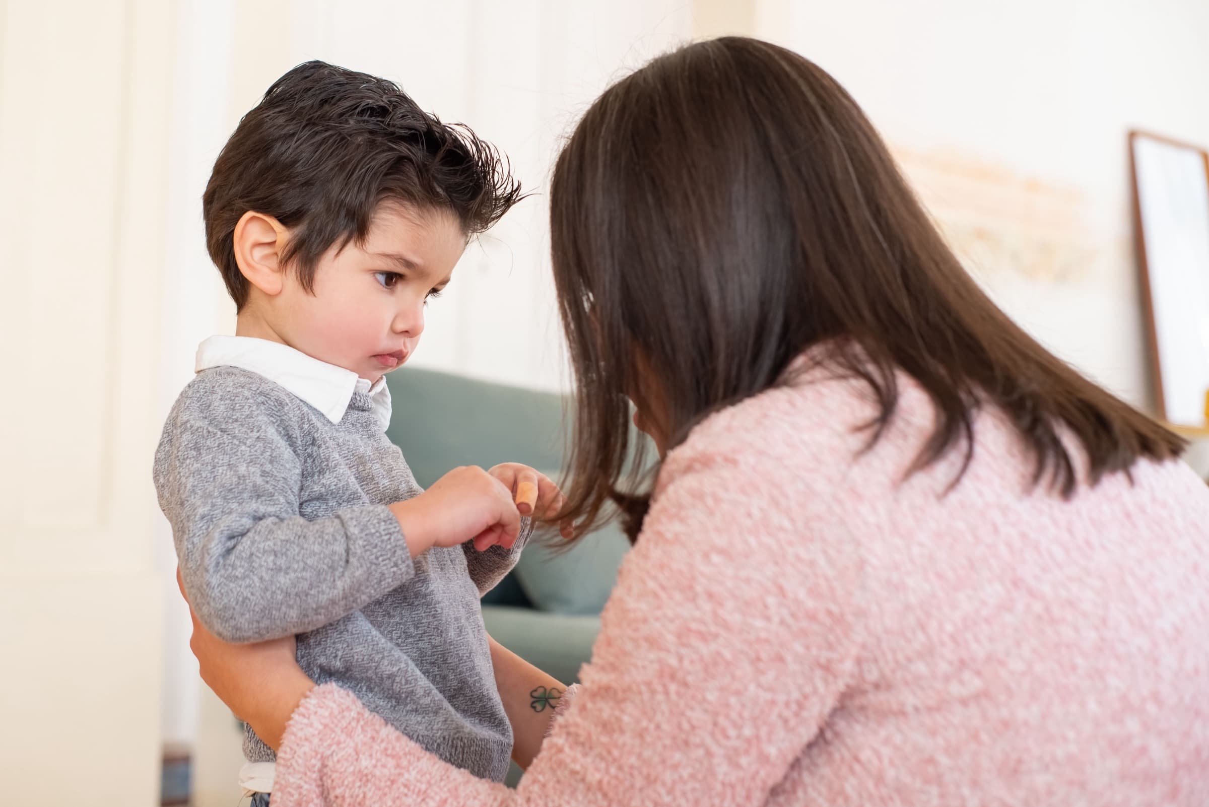 A mother tenderly consoling her young child in a warm, softly lit room at home
